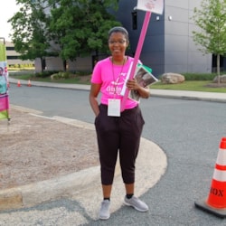 A Girls on the Run volunteer holds up "Ask Me" sign to direct 5k participants on where to go