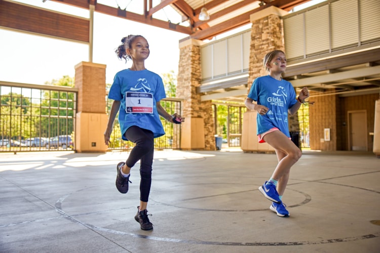 Girls on the Run participants run outside during program practice smiling